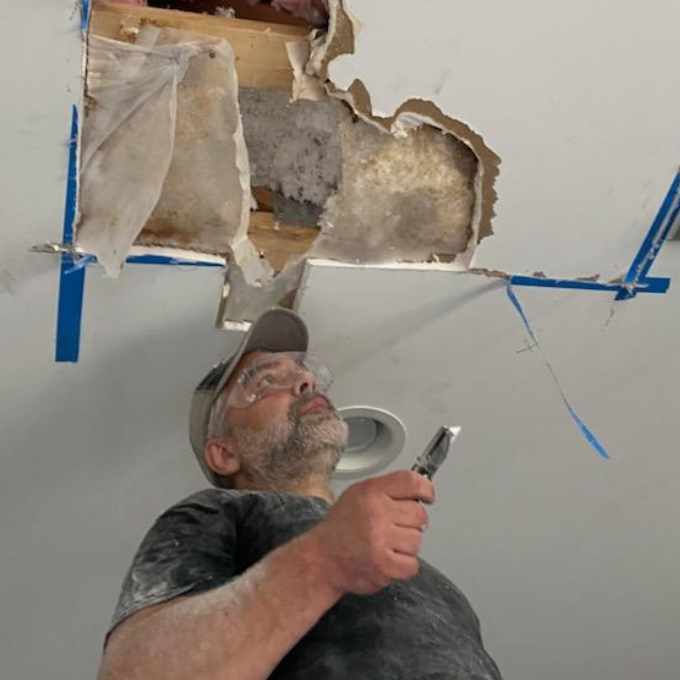 Home renovation worker assessing ceiling damage.