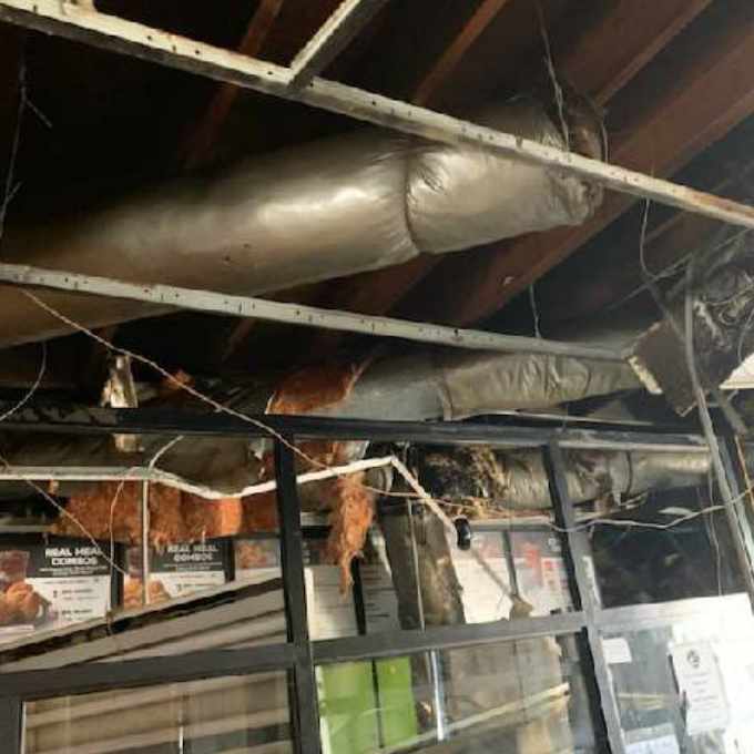 Damaged ceiling with exposed insulation and pipes