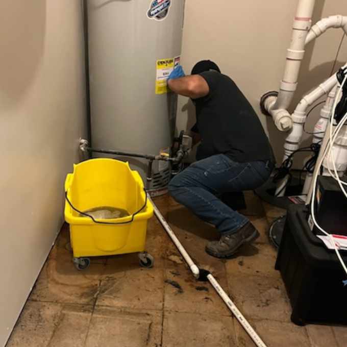 A worker repairing a water heater in a home