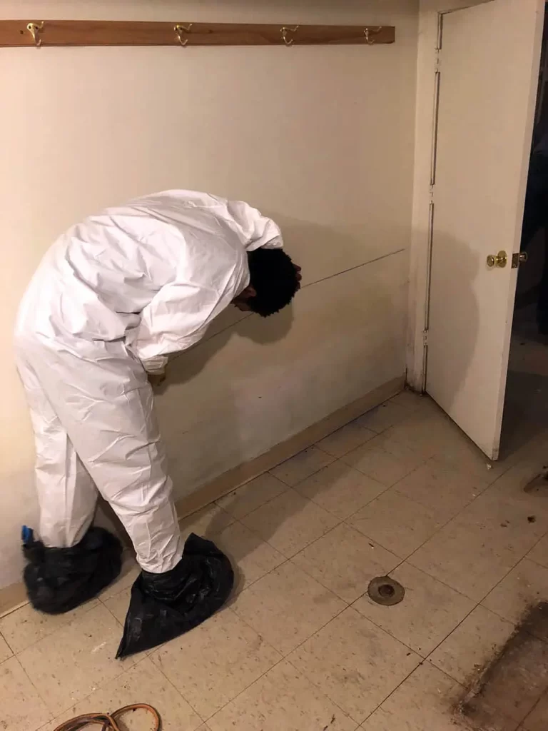 Worker in protective gear inspecting a wall