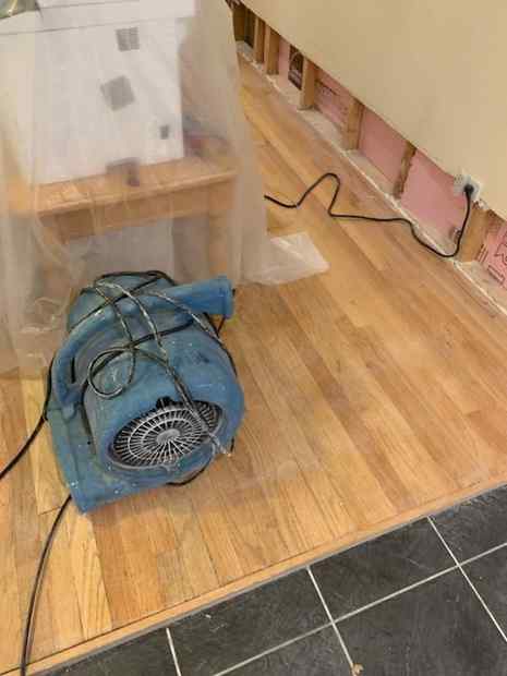 Air mover drying a flood-cut wall with exposed insulation after water damage in a Chicago basement