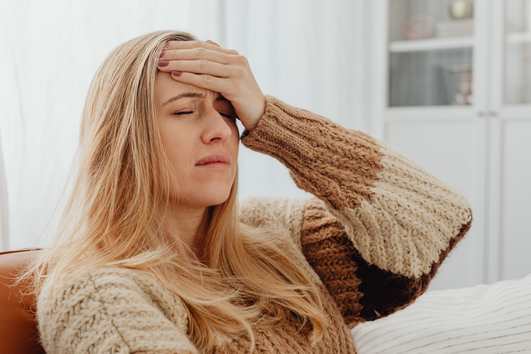 Tired woman with a headache at home, a possible sign of mold exposure