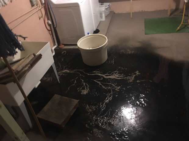 Raw sewage backup flooding a Chicago basement floor with dark contaminated black water