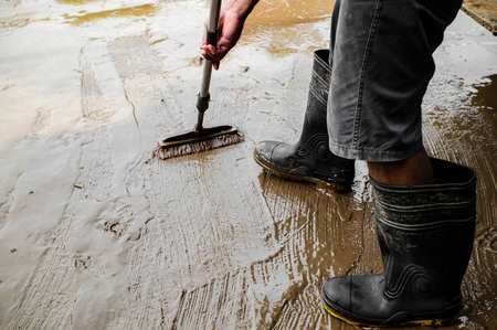 Worker in rubber boots removing muddy sewage water during cleanup in Chicago
