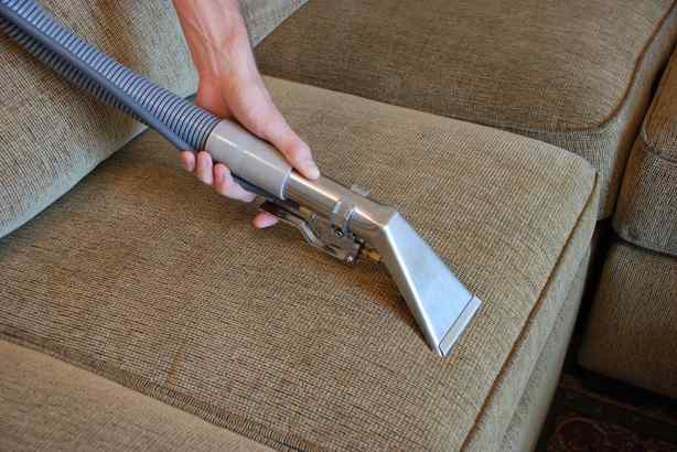 Professional upholstery cleaning wand extracting dirt from a fabric couch cushion in Chicago