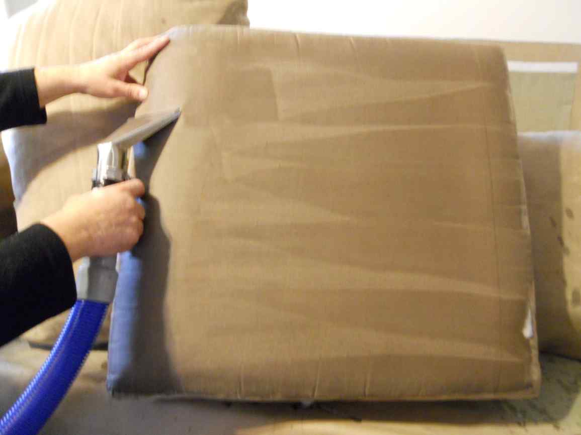 Upholstery cleaning wand removing dirt and stains from a sofa cushion in Chicago